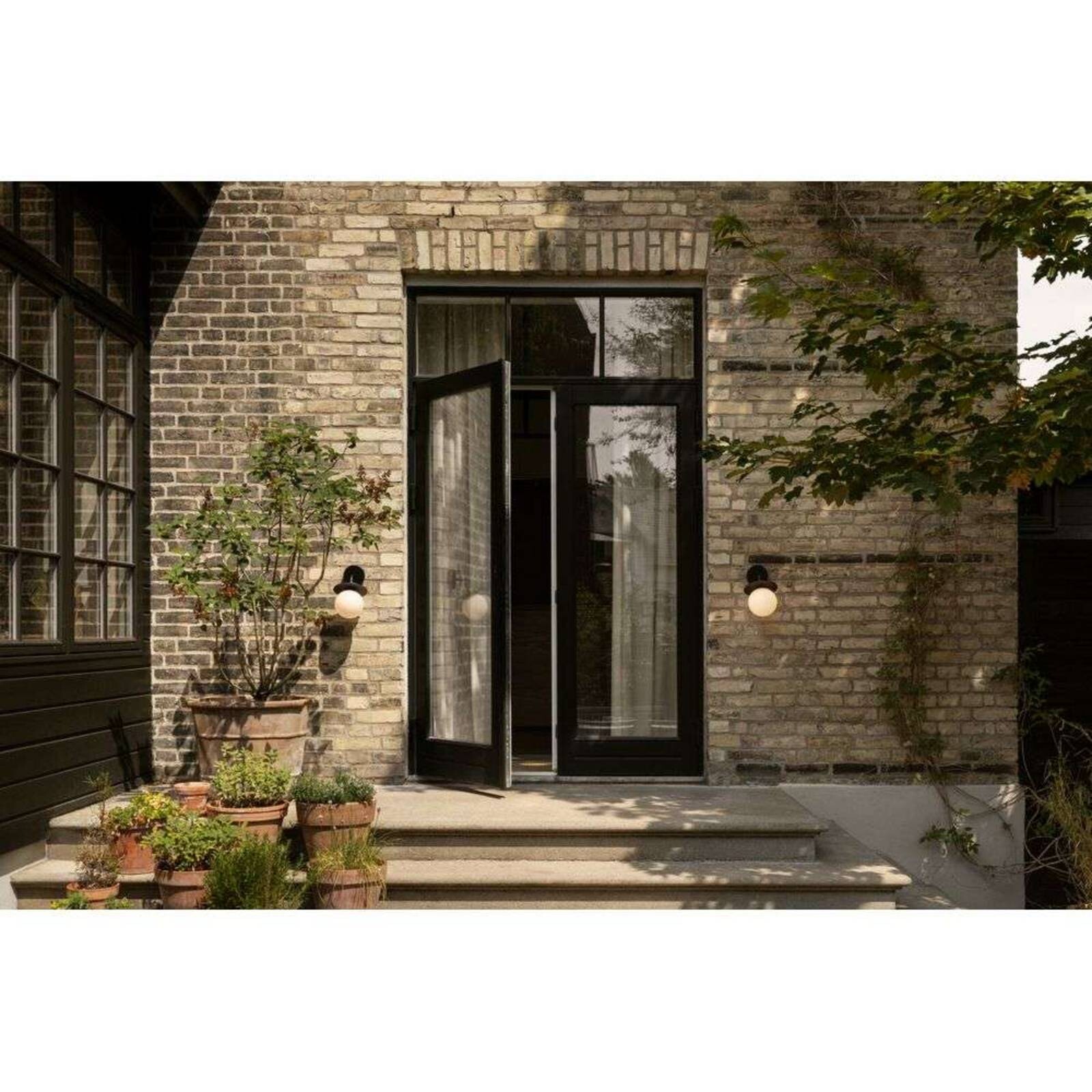 Nuura Vonkajšie nástenné svietidlo Liila, šírka 16 cm, čierna/opálová